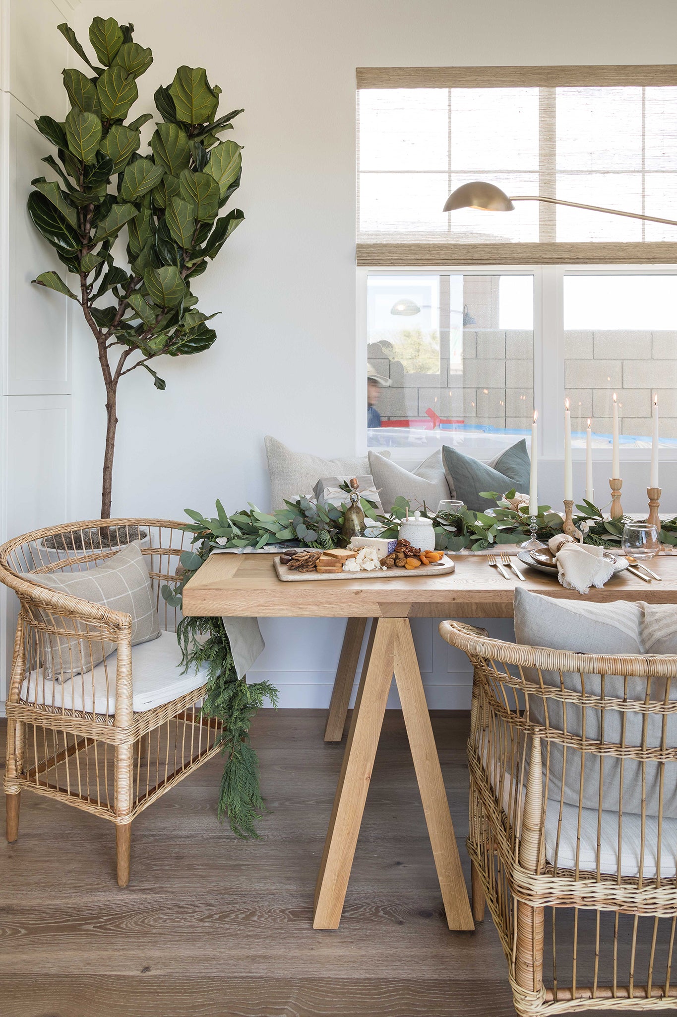 A beautifully styled dining space featuring natural rattan dining chairs, a solid timber table, and an elegant table ascape with candles and greenery, creating a warm and inviting atmosphere