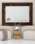 Nash chairs in natural upholstery styled with a timber side table, ceramic vase, and elephant wall art in a bright, whitewashed interior.