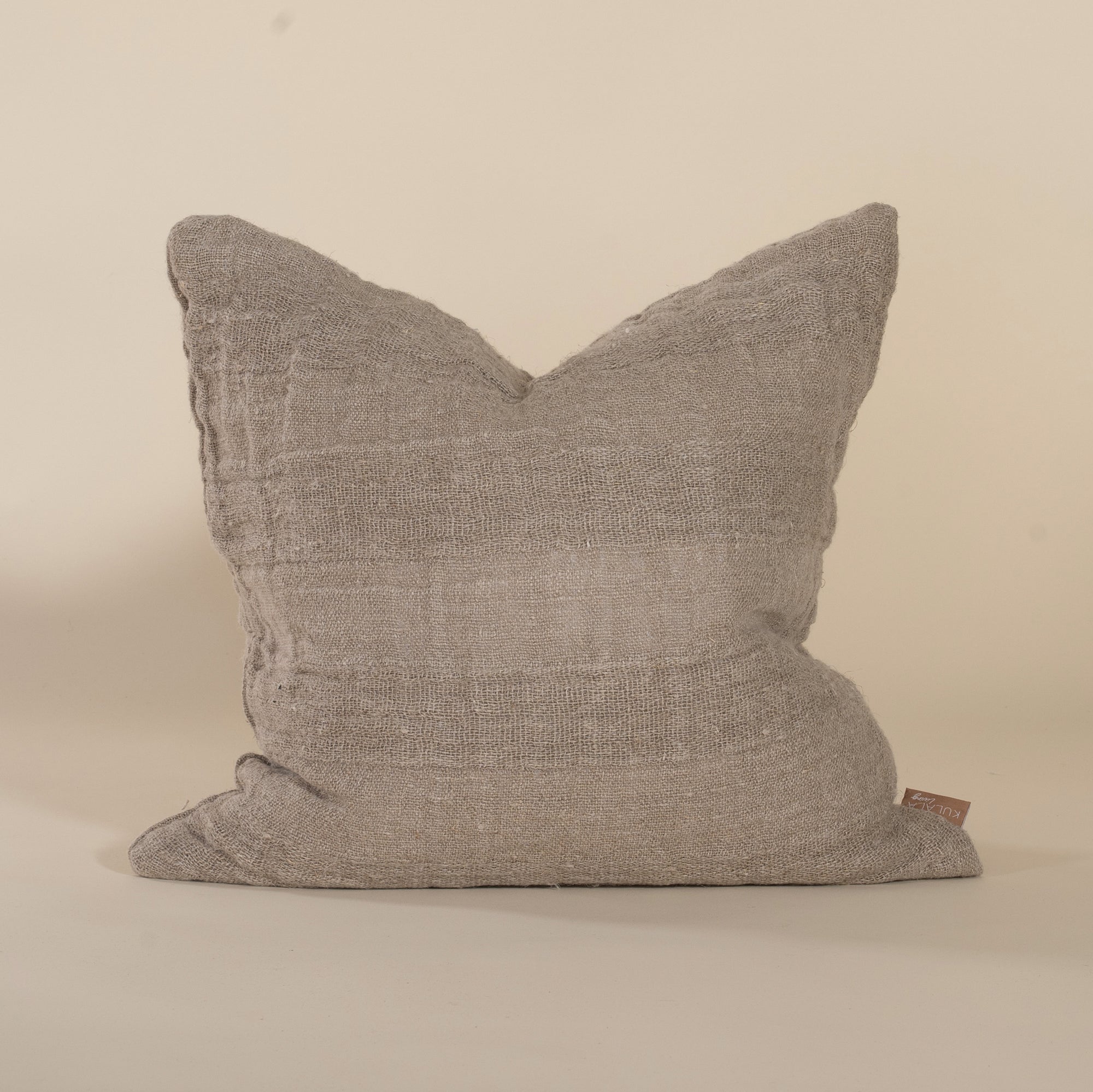 Natural linen cushion with a textured finish in a soft, neutral tone, perfect for adding warmth and comfort to any living space