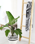 A natural wooden ladder styled as a towel and blanket rack in a modern boho-inspired interior. Paired with a tropical plant in a black-and-white patterned pot, this piece adds warmth and texture to any home