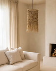 Natural woven pendant light with organic fringe detail hanging above a neutral linen sofa in a soft, minimalist living room