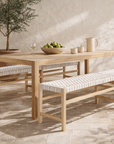 Nayasa bench in natural timber with white woven seat styled in a mediterranean dining space with stone floor and soft filtered light