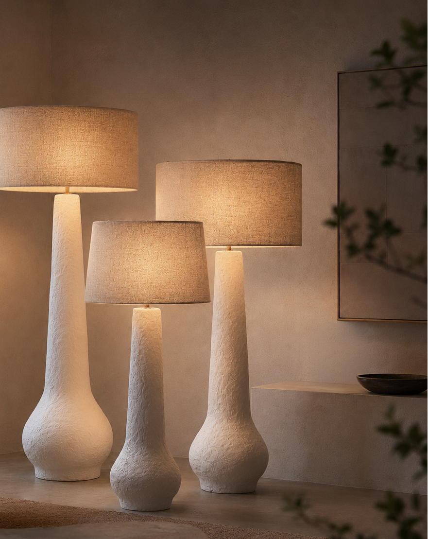 Nhoma lamps in small, medium and large sizes with linen shades styled together in a calm neutral interior, creating layered ambient lighting and sculptural presence.