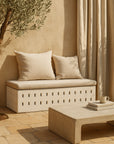 Niche Coffee Table in a low rectangular form with curved edges, styled in an outdoor setting with a sculptural bench seat and soft neutral cushions