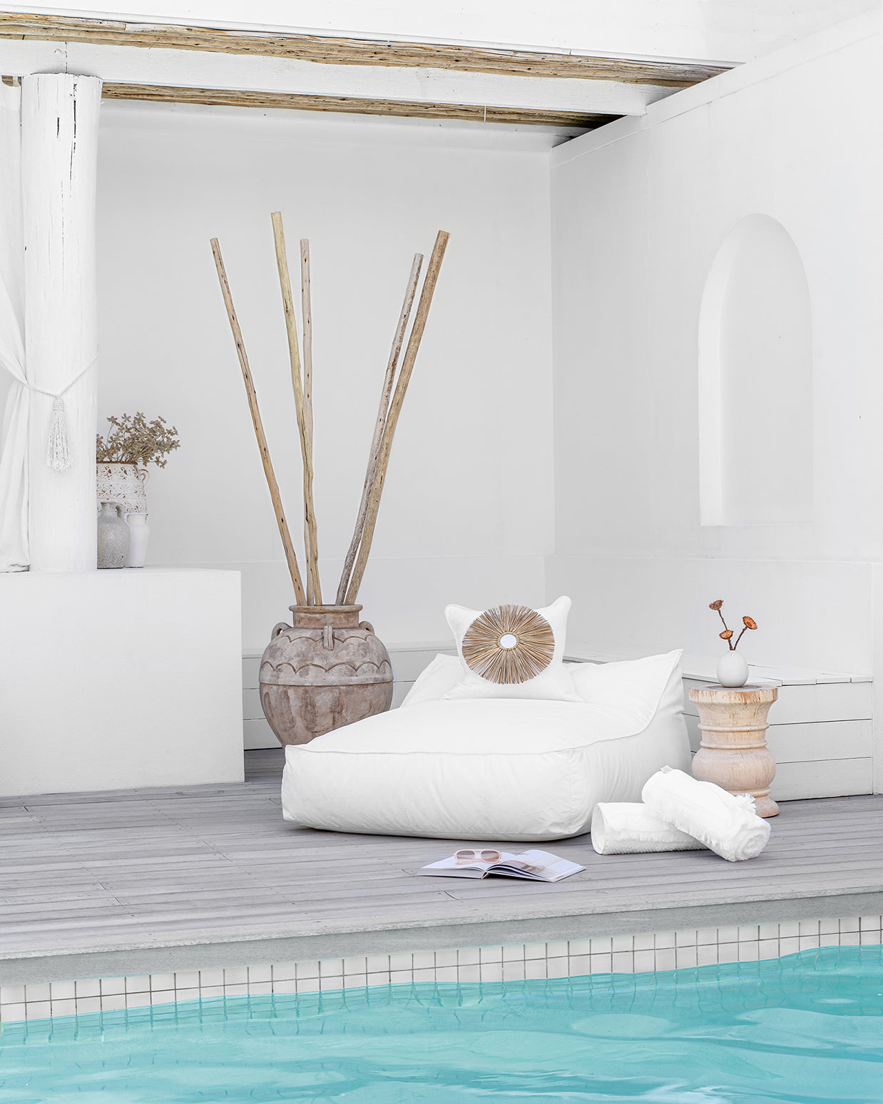 White outdoor beanbag by the poolside, styled with a white decorative cushion, rustic wooden side table, and natural decor accents, creating a serene and stylish relaxation space.