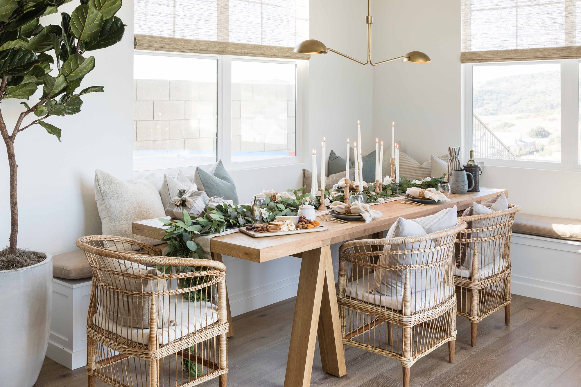 A beautifully styled dining space featuring natural rattan dining chairs, a solid timber table, and an elegant table scape with candles and greenery, creating a warm and inviting atmosphere