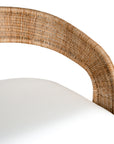 A rattan armchair featuring a curved backrest and a plush white upholstered seat. This coastal-inspired piece combines natural textures with modern comfort, ideal for relaxed living spaces
