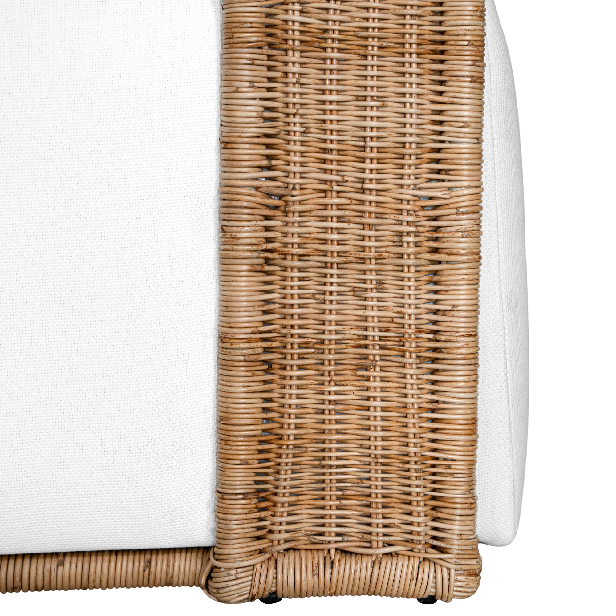 A rattan armchair featuring a curved backrest and a plush white upholstered seat. This coastal-inspired piece combines natural textures with modern comfort, ideal for relaxed living spaces