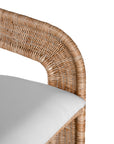 A natural rattan bar stool with a curved backrest and a white upholstered cushion. The woven texture and sturdy frame bring a relaxed yet sophisticated coastal-inspired aesthetic to any bar or kitchen counter