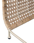 Modern coastal rattan lounge chair with curved silhouette and open weave pattern, featuring a natural finish and sleek white metal frame
