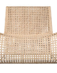 Modern coastal rattan lounge chair with curved silhouette and open weave pattern, featuring a natural finish and sleek white metal frame