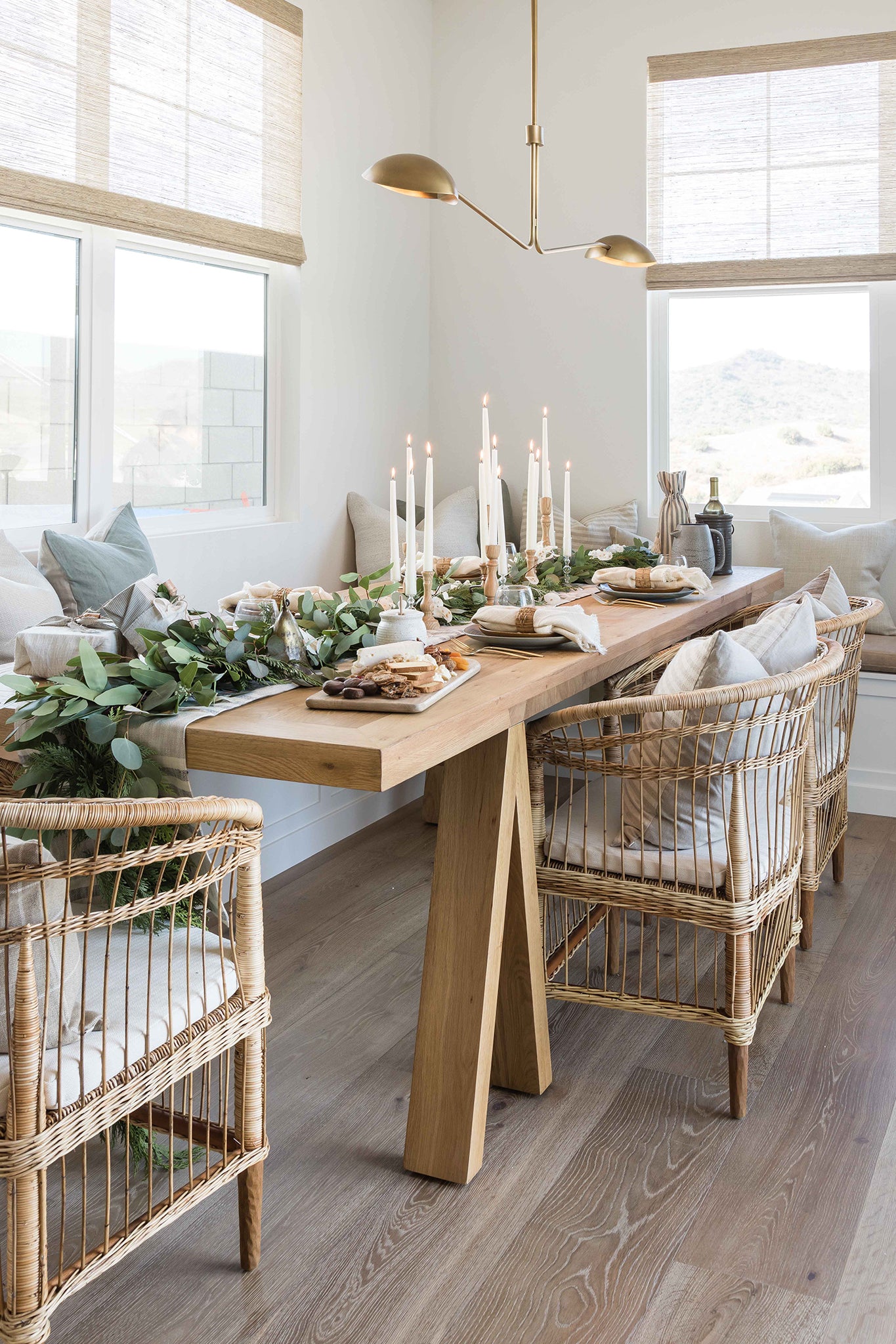 A beautifully styled dining space featuring natural rattan dining chairs, a solid timber table, and an elegant table scape with candles and greenery, creating a warm and inviting atmosphere