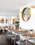Modern restaurant interior featuring wooden dining chairs with woven rope seats and natural wood tabletops, creating a relaxed coastal ambiance.