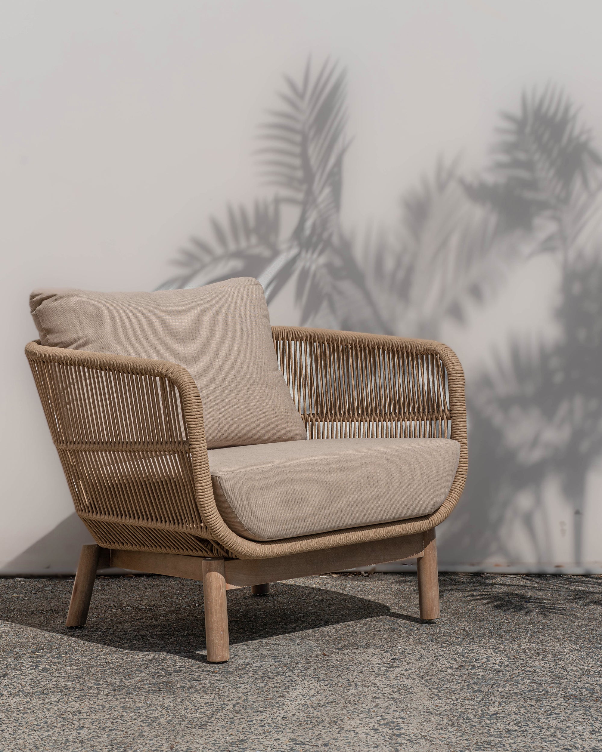 A stylish rope weave armchair with a natural wood frame and soft linen cushions. Designed for both indoor and outdoor use, this chair offers a relaxed, contemporary aesthetic perfect for modern and coastal-inspired interiors