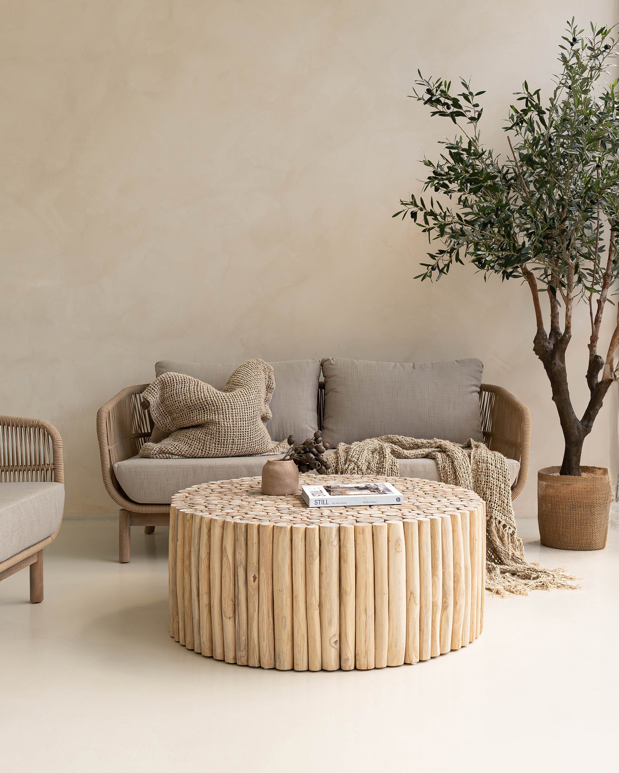 A beautifully styled living space featuring a natural rope weave lounge set with plush grey cushions, complemented by a rustic wooden coffee table and textured decor. Perfect for indoor or covered outdoor relaxation with a contemporary coastal aesthetic