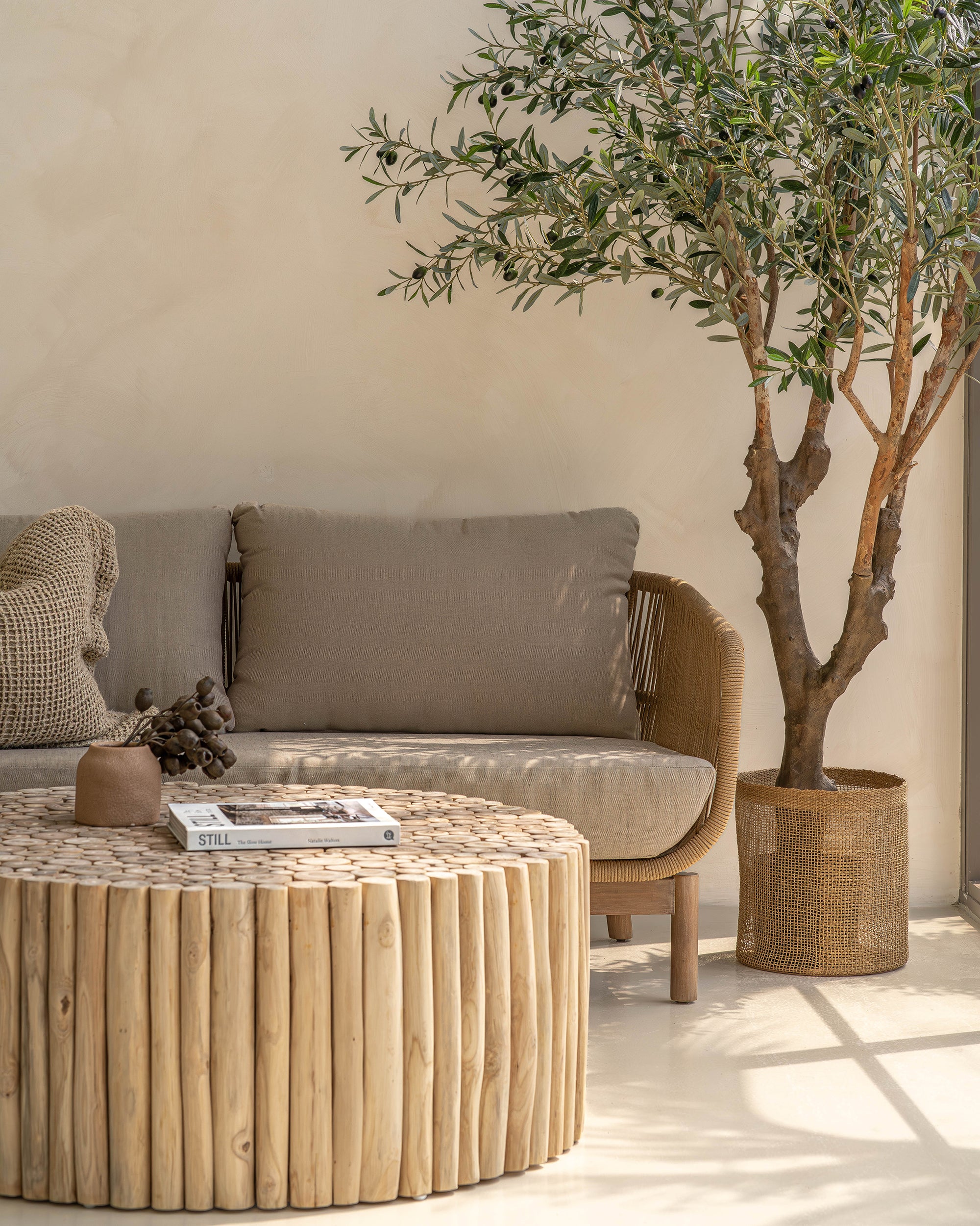A beautifully styled living space featuring a natural rope weave lounge set with plush grey cushions, complemented by a rustic wooden coffee table and textured decor. Perfect for indoor or covered outdoor relaxation with a contemporary coastal aesthetic.