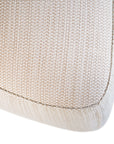 Curved upholstered ottoman with natural textured fabric and subtle black feet, ideal for contemporary living spaces