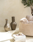 Pair of striped paper mache vases styled on a neutral surface, accompanied by books and a ceramic cup, creating a modern bohemian aesthetic.
