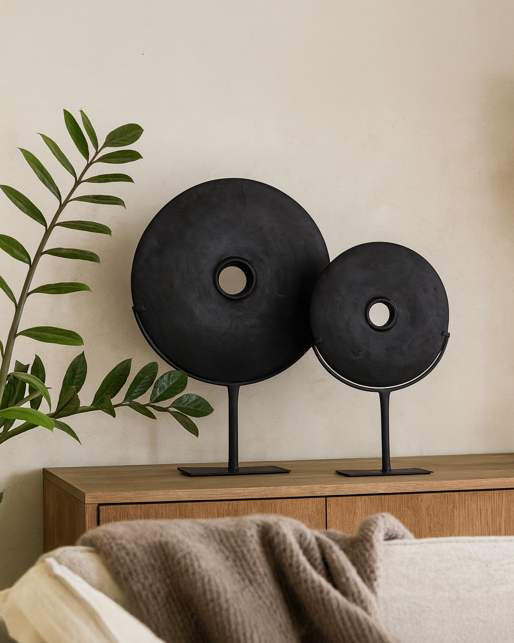 Tata Decorative Discs in matte black finish displayed on metal stands, styled on a timber sideboard in a modern living room with soft natural tones and greenery