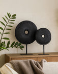 Tata Decorative Discs in matte black finish displayed on metal stands, styled on a timber sideboard in a modern living room with soft natural tones and greenery