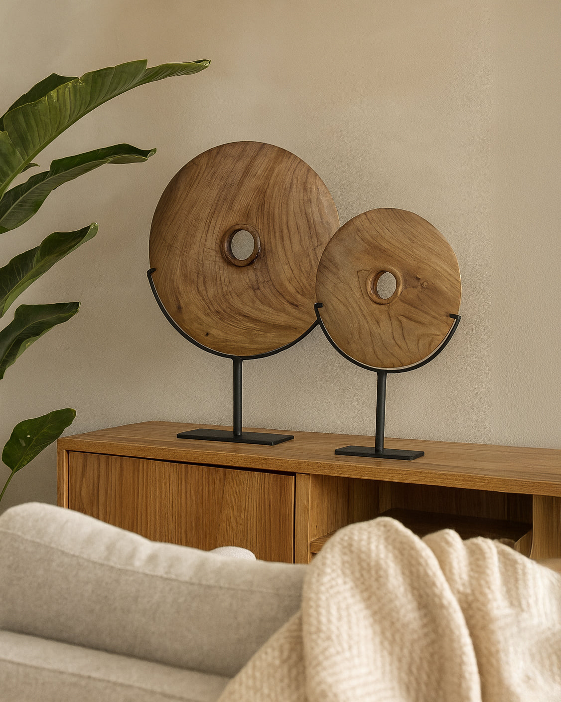 Tata Decorative Discs handcrafted from teak timber displayed on black metal stands, styled on a timber sideboard in a modern neutral living room