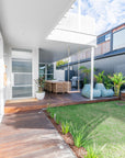 A spacious outdoor dining setting featuring a solid teak table and matching slatted dining chairs, designed for elegant alfresco entertaining on a timber deck