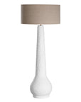 A textured paper mache white table lamp with elongated sculptural base and neutral linen shade, adding a refined and organic touch to any interior space