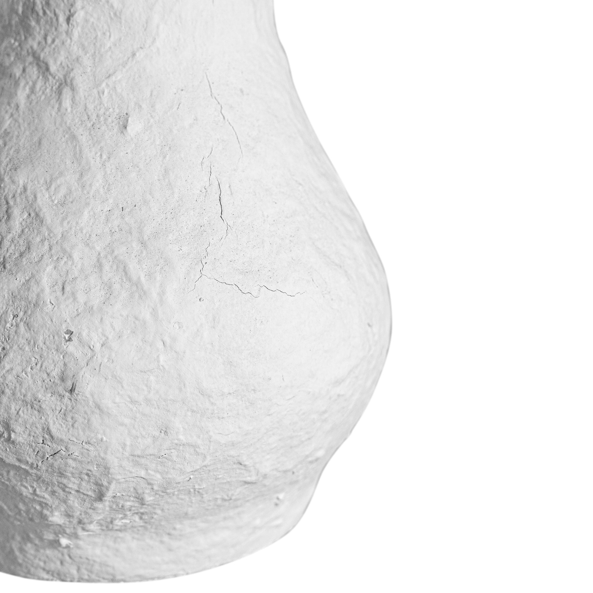 A textured paper mache white table lamp with elongated sculptural base and neutral linen shade, adding a refined and organic touch to any interior space
