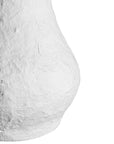 A textured paper mache white table lamp with elongated sculptural base and neutral linen shade, adding a refined and organic touch to any interior space