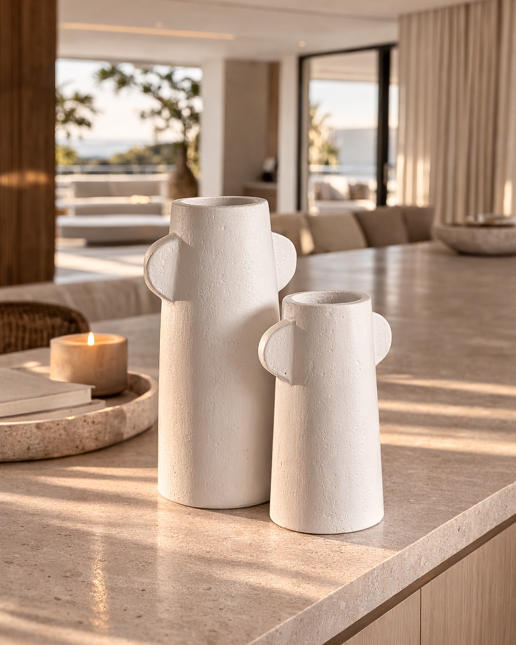 Umbono vase cluster in soft white textured finish with sculptural handles styled on a sunlit stone surface.
