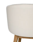 A modern upholstered dining chair featuring a curved backrest and soft white fabric, supported by sturdy oak timber legs with a natural finish