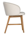 A modern upholstered dining chair featuring a curved backrest and soft white fabric, supported by sturdy oak timber legs with a natural finish