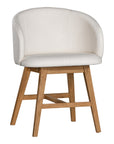 A modern upholstered dining chair featuring a curved backrest and soft white fabric, supported by sturdy oak timber legs with a natural finish