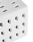 A modern white concrete side table with perforated details, blending sculptural design with functional seating for indoor and outdoor spaces