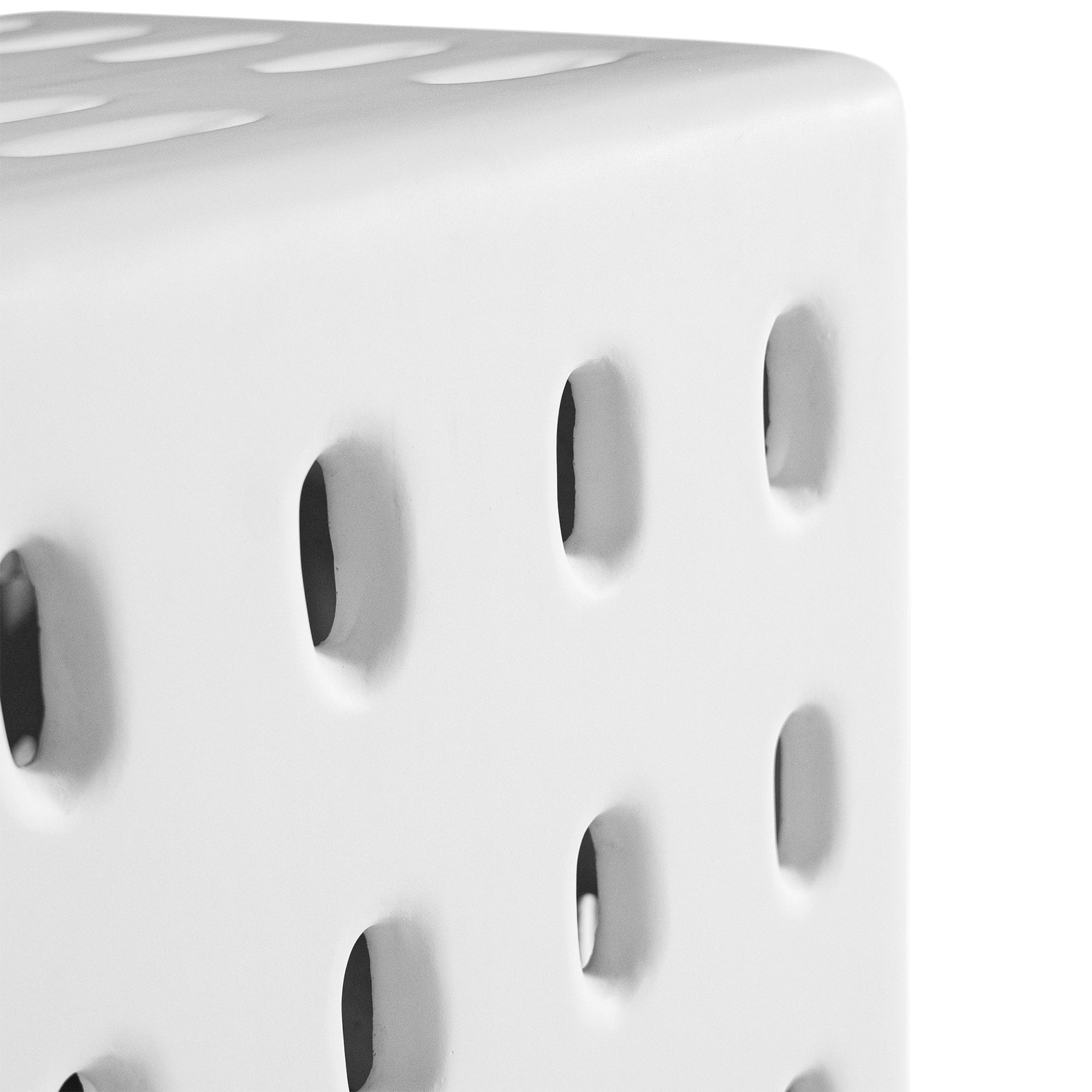 A modern white concrete side table with perforated details, blending sculptural design with functional seating for indoor and outdoor spaces