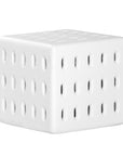 A modern white concrete side table with perforated details, blending sculptural design with functional seating for indoor and outdoor spaces