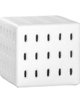 A modern white concrete side table with perforated details, blending sculptural design with functional seating for indoor and outdoor spaces