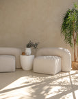 Modern white magnesium oxide side table styled with a ceramic vase and dried florals, complementing a neutral-toned curved sofa
