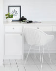 Coastal home office with white rattan desk chair and minimal decor, featuring natural elements and crisp white cabinetry