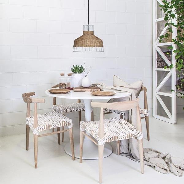 White round dining table with natural timber chairs featuring white woven seats, creating a contemporary and relaxed dining setting