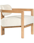 Stylish wooden occasional chair with boucle upholstery, set in a minimalist dining space with a sculptural stone table and an olive tree in a textured planter