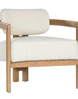 Stylish wooden occasional chair with boucle upholstery, set in a minimalist dining space with a sculptural stone table and an olive tree in a textured planter
