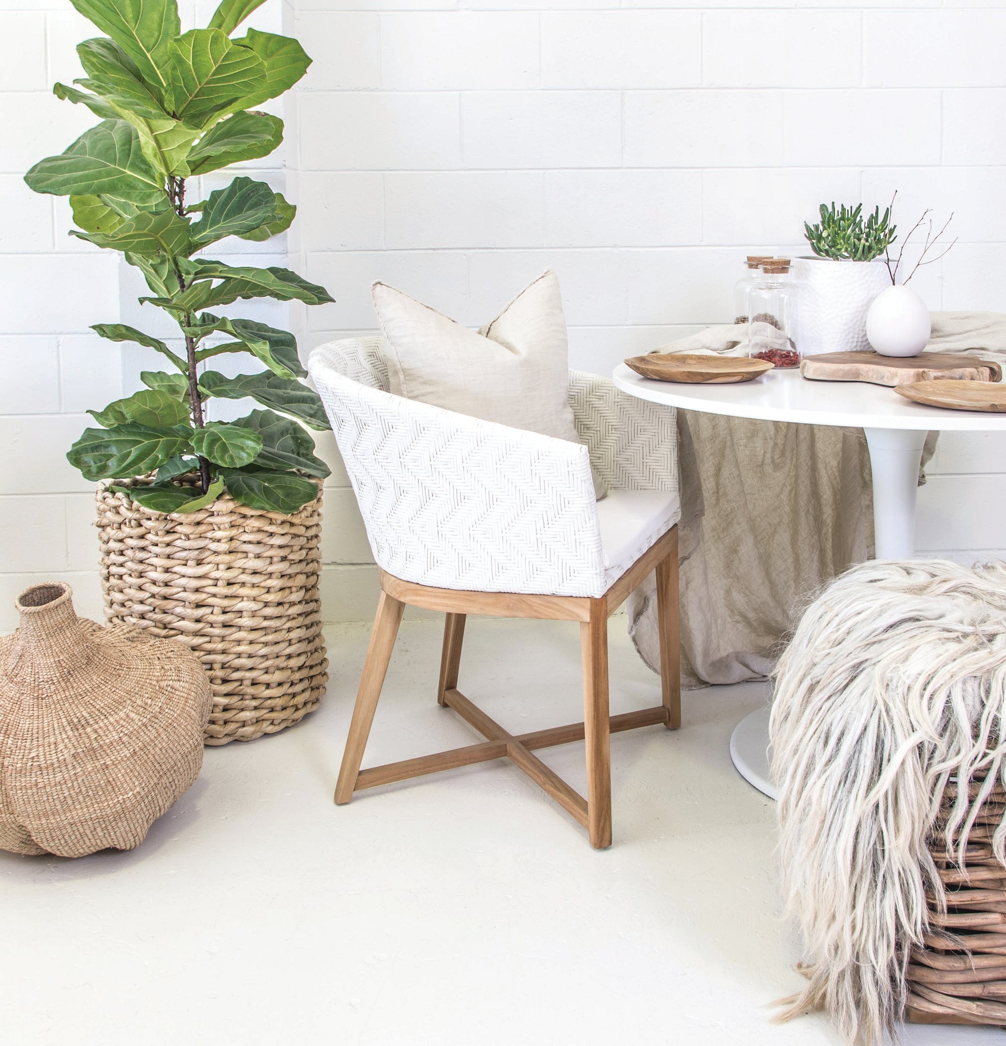 KULALA Living handwoven rattan dining chair with a curved backrest, natural wood legs, and a white seat cushion, blending coastal and contemporary design