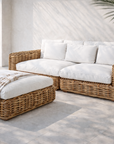 Zambezi rattan sofa and ottoman with white cushions styled poolside in a mediterranean outdoor setting with soft natural light