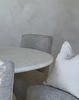 KULALA Living modern dining room with a sculptural travertine table, textured upholstered chairs, and a handcrafted paper mâché vase, creating a serene and elegant space