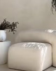 Modern white magnesium oxide side table styled with a ceramic vase and dried florals, complementing a neutral-toned curved sofa