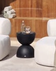 Modern outdoor lounge setting featuring a curved cream upholstered sofa on a tiled deck, set against black timber-clad house with forest backdrop – KULALA Living.