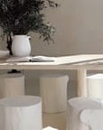 Hyrdo-dipped dining table styled with white timber stump stools, neutral linen napkins, and ceramic tableware. A soft, sunlit setting with organic textures and natural elements, creating a relaxed, earthy ambiance
