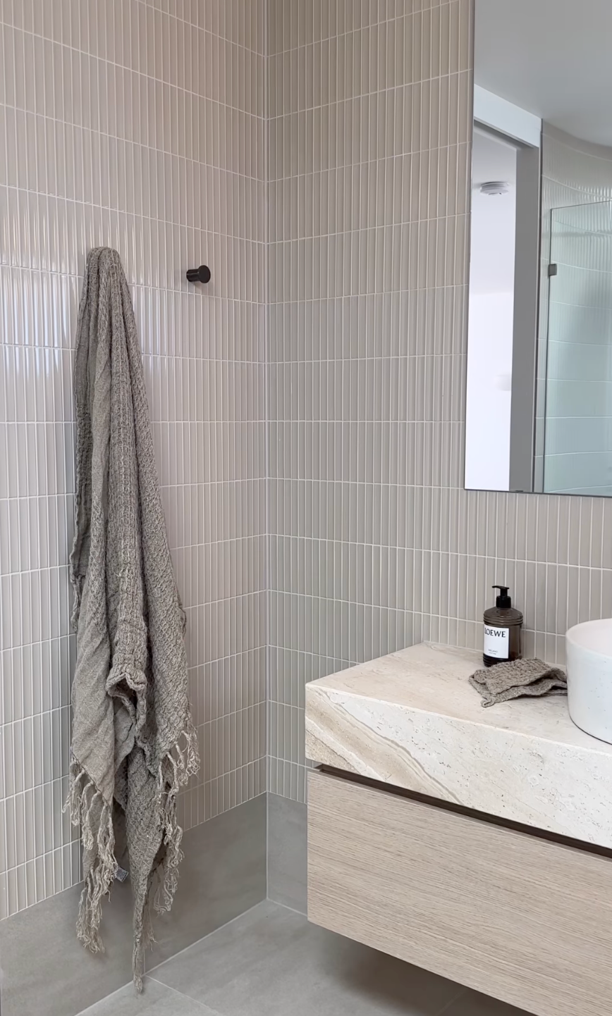 Wall-mounted towel hook in a minimalist neutral toned bathroom and vanity.