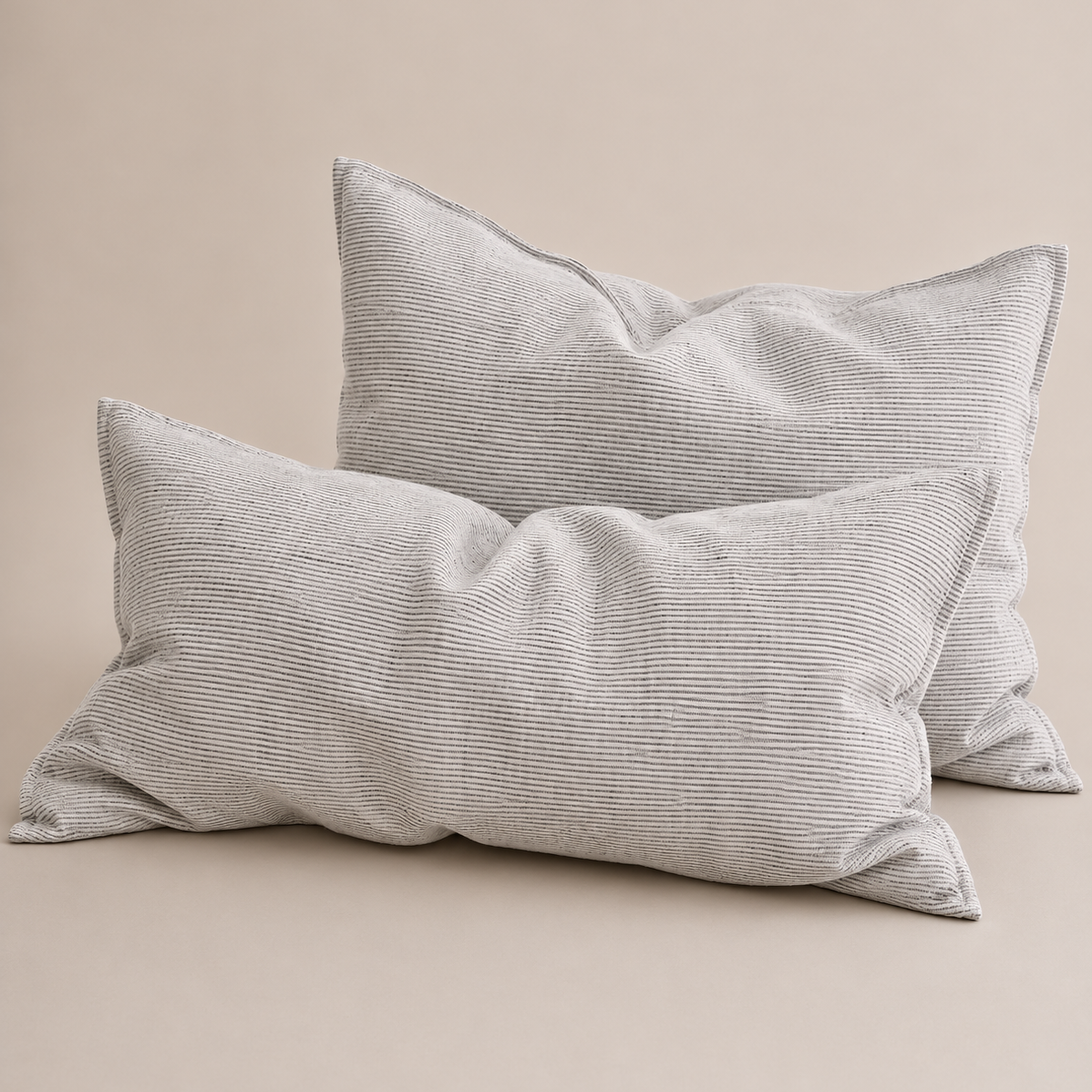 Two light gray ribbed lumbar pillows with a textured corduroy-like fabric, arranged on a solid beige background.